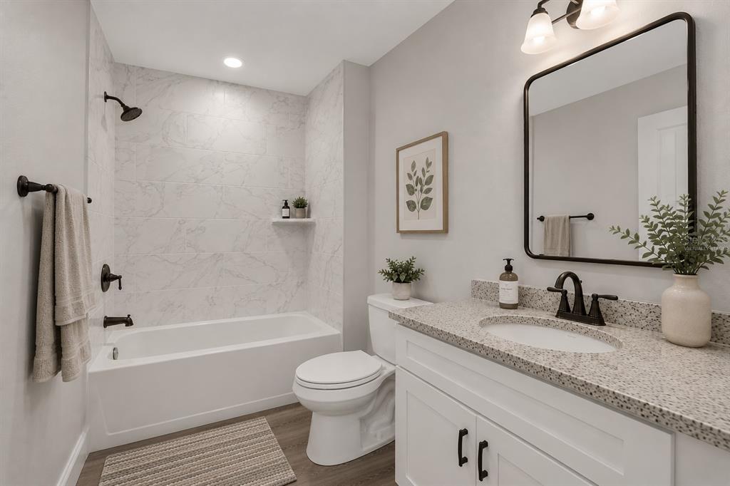 A bathroom features a white vanity with a speckled countertop, a toilet, and a tub-shower — 4368 MERCEDES STREET, SEBRING, FL