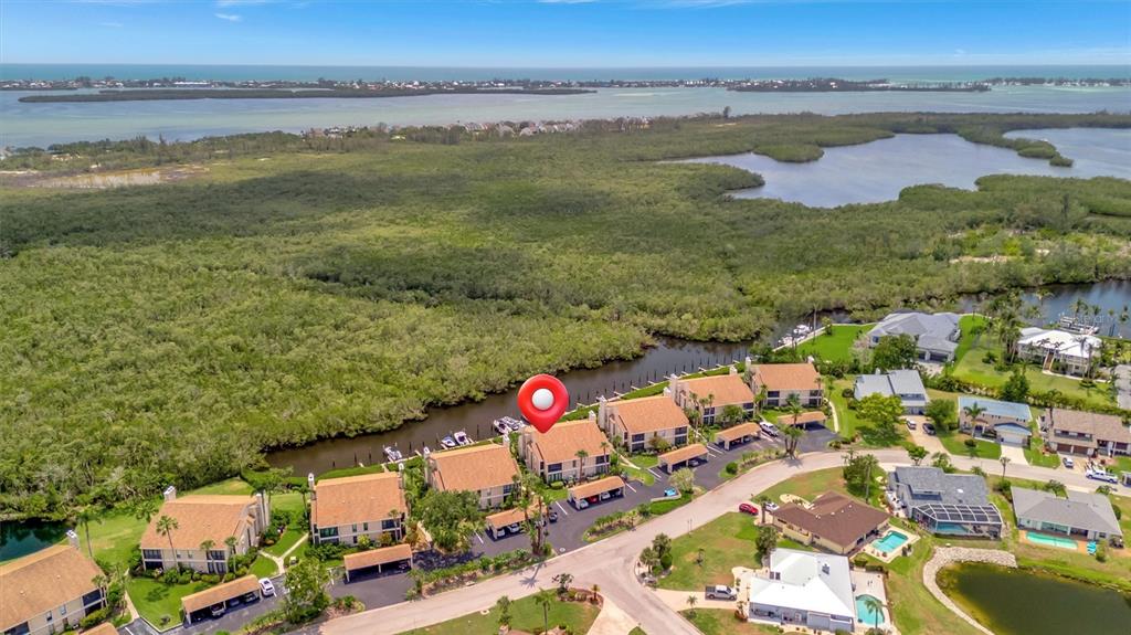 An aerial view shows a residential complex with tan buildings situated near mangroves and water — 8710 54TH AVENUE W UNIT 8710, BRADENTON, FL