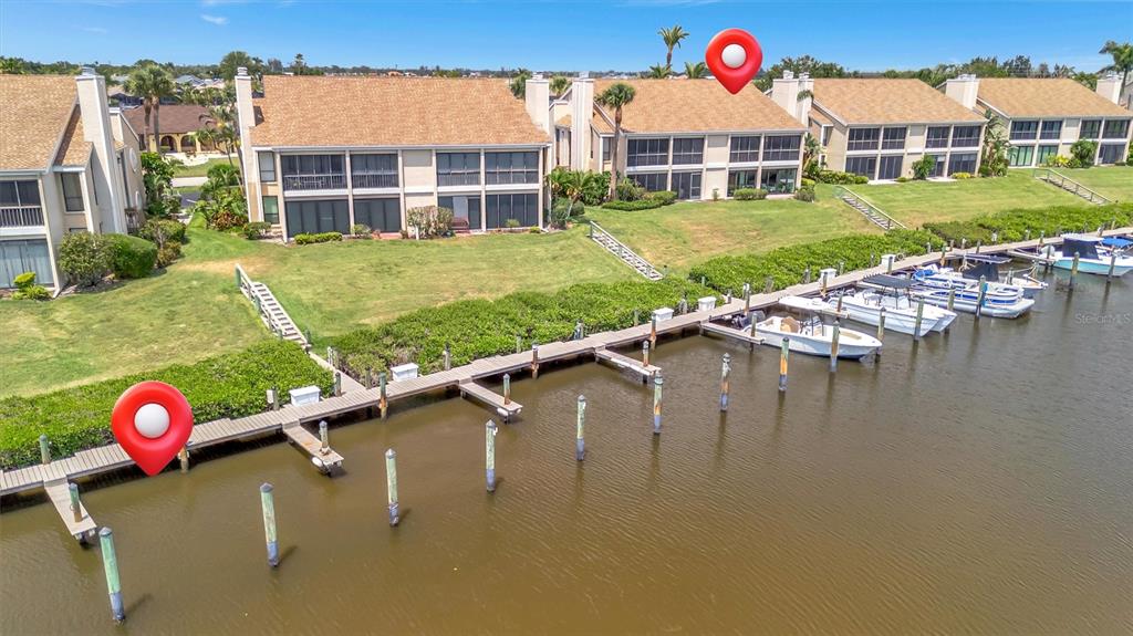 An aerial view shows waterfront townhomes with a wooden boat dock and several docked boats — 8710 54TH AVENUE W UNIT 8710, BRADENTON, FL
