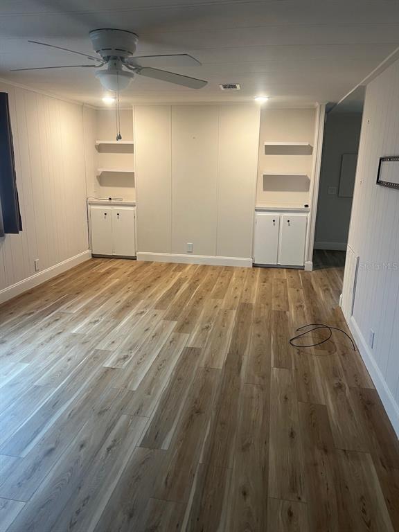 A room with light wood-look flooring, a ceiling fan, and built-in cabinets with shelving — 12343 LARIAT WAY, HUDSON, FL