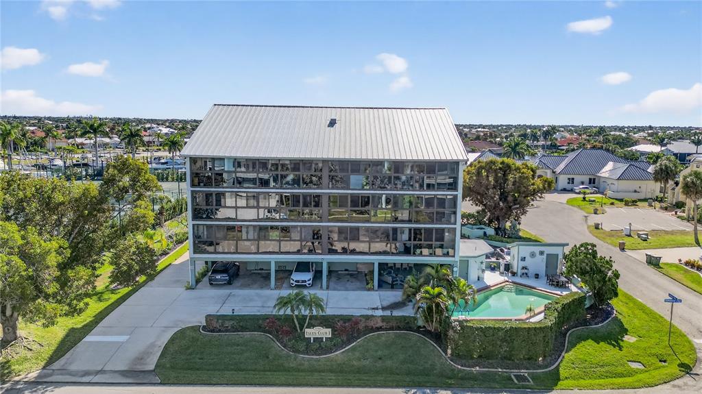 An aerial view of a multi-story apartment building with a pool and covered parking — 1765 JAMAICA WAY UNIT 101, PUNTA GORDA, FL