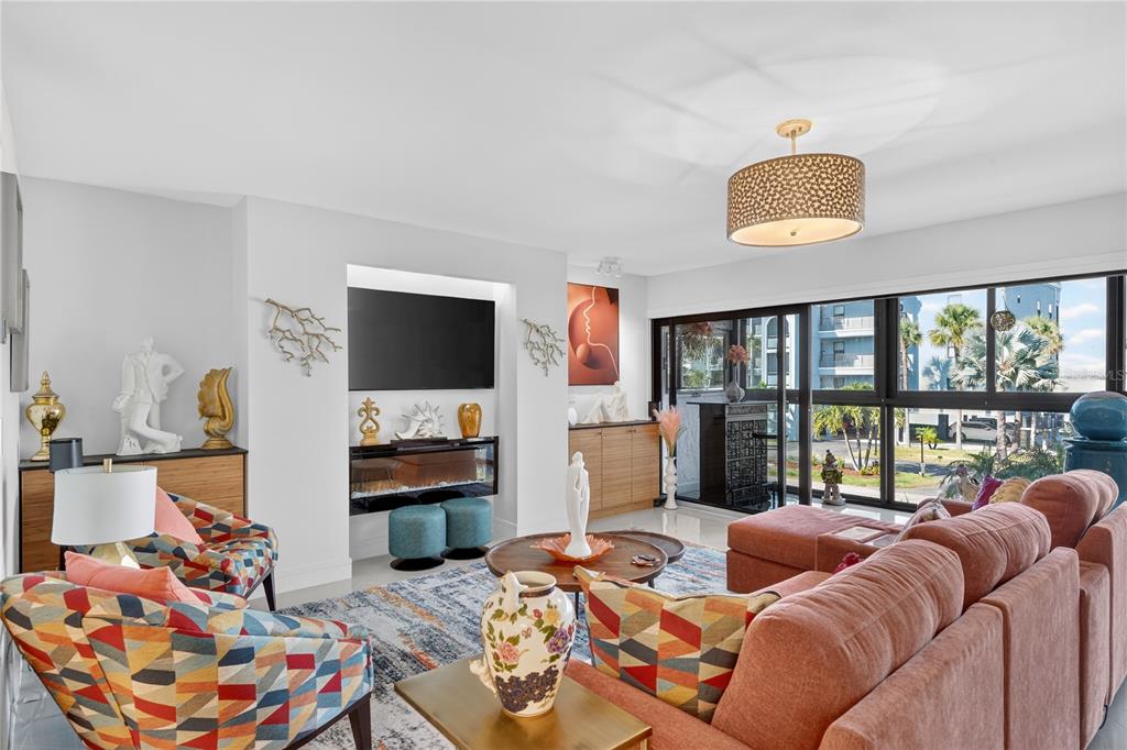 A living room features a patterned armchair, a large sectional sofa, and a wall-mounted television — 1765 JAMAICA WAY UNIT 101, PUNTA GORDA, FL