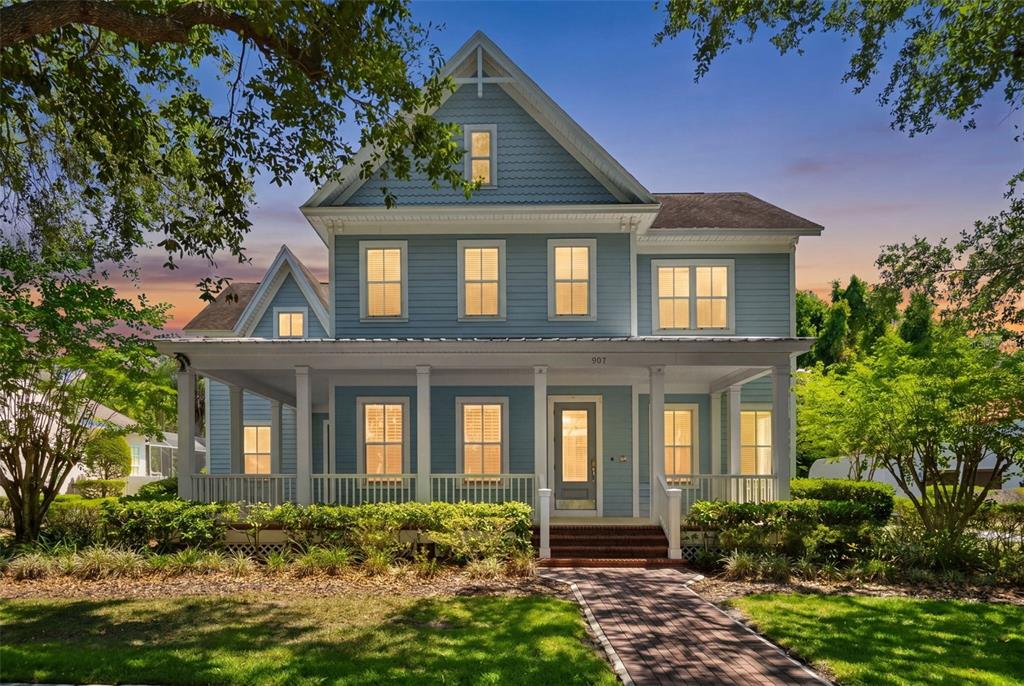 A two-story blue house with a front porch and a brick walkway at dusk — 907 WESTPARK DRIVE, CELEBRATION, FL