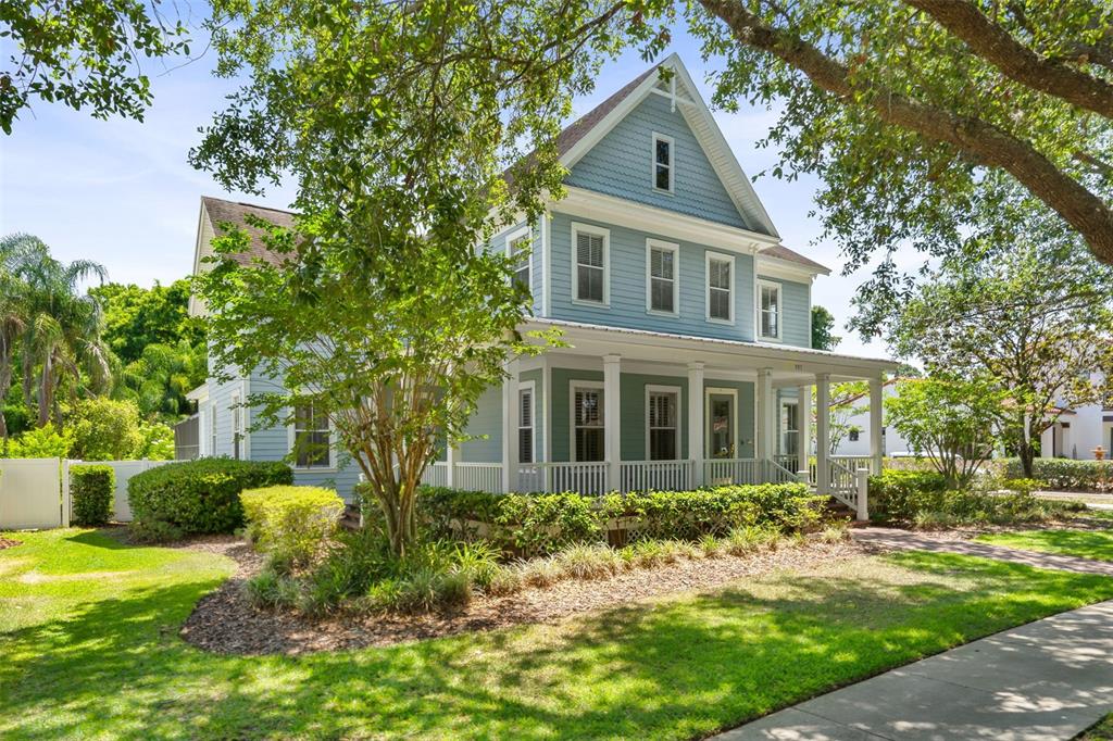 A two-story blue house with a wrap-around porch and white trim sits on a lawn — 907 WESTPARK DRIVE, CELEBRATION, FL