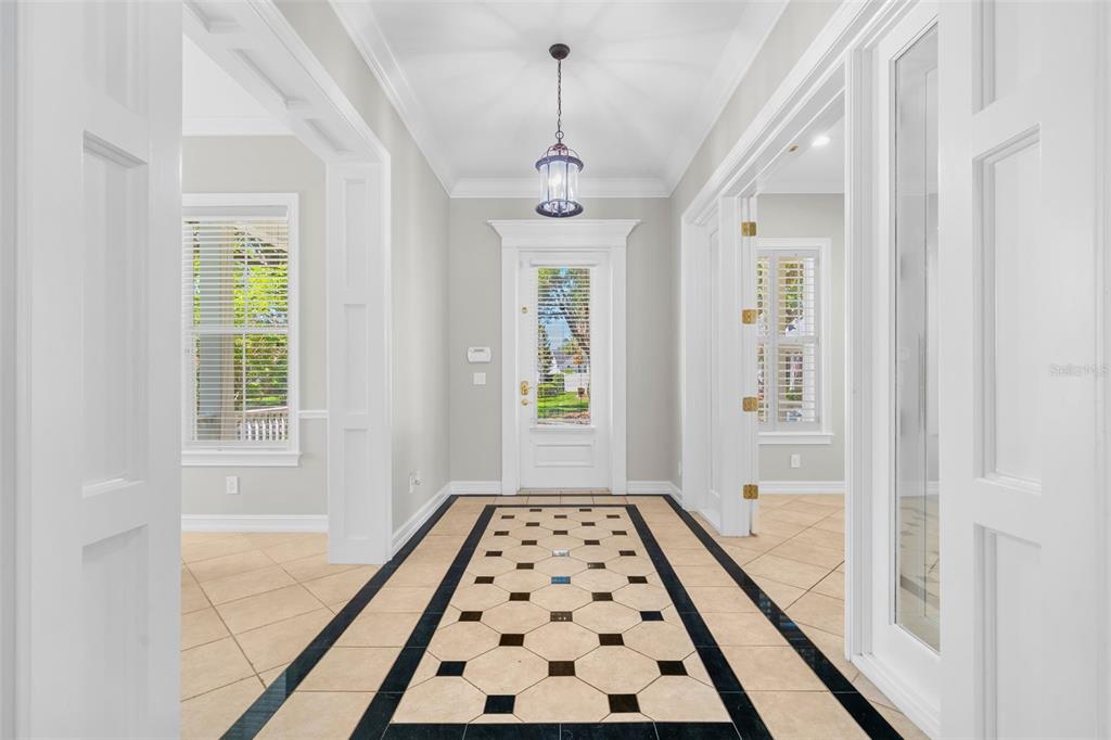 A bright entryway features a patterned tile floor, white trim, and a glass-paneled front door — 907 WESTPARK DRIVE, CELEBRATION, FL