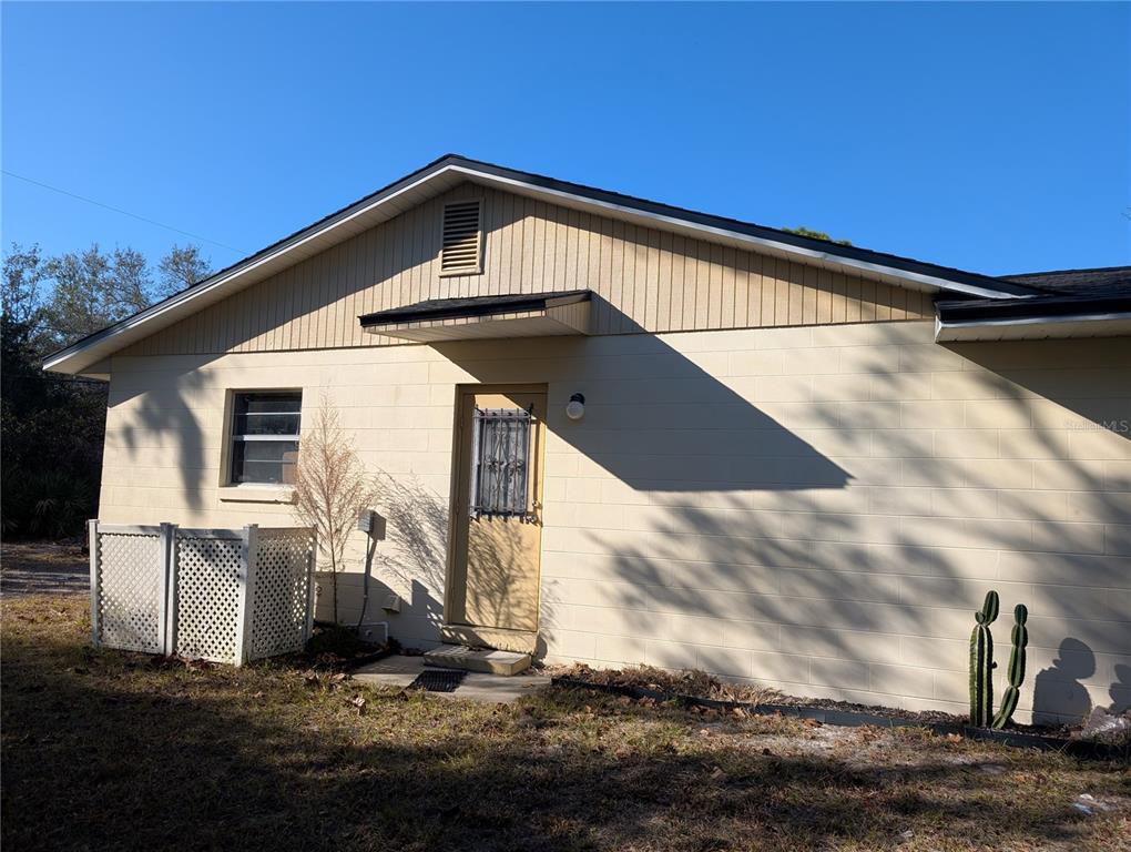 A beige concrete block house exterior features a single door, a window, and a cactus — 24 S COURTLAND BOULEVARD, DELTONA, FL