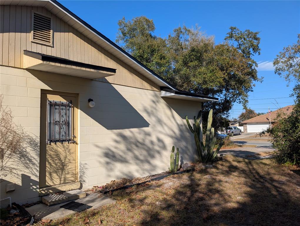 A tan concrete block house exterior features a door with a security grate and cacti — 24 S COURTLAND BOULEVARD, DELTONA, FL