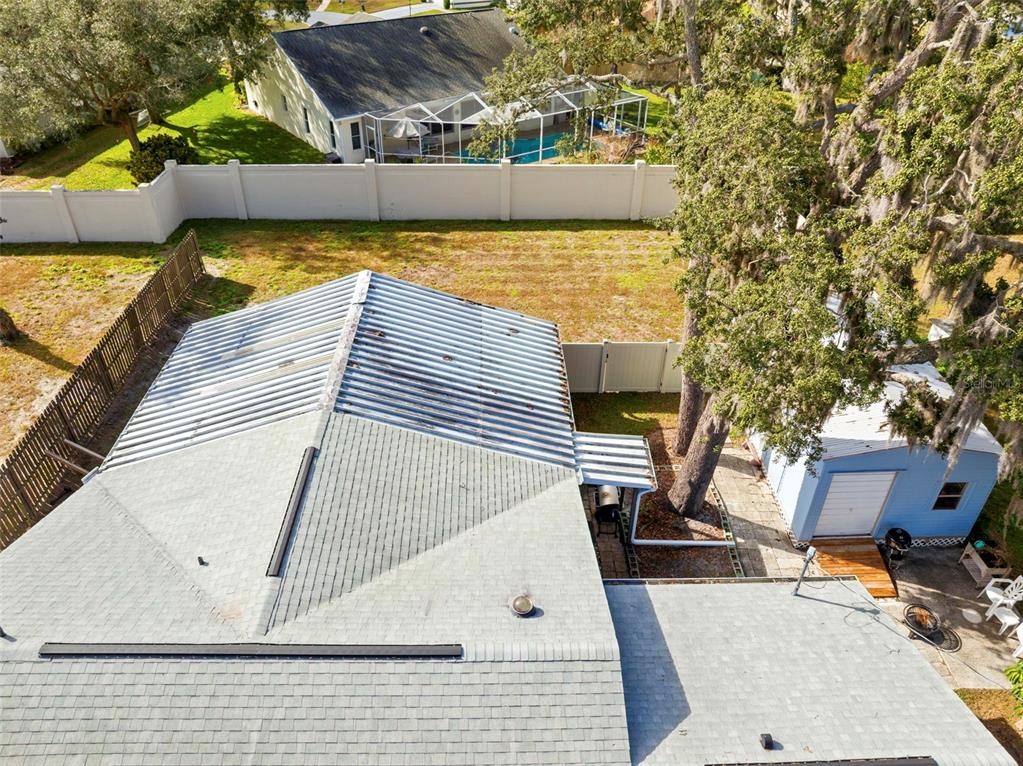 An aerial view shows a house with a metal roof section, a shed, and trees — 2399 GALLAGHER AVENUE, SPRING HILL, FL
