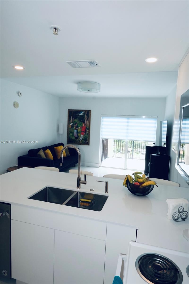 A modern kitchen island with a double sink overlooks a living area with a sofa — 3410 Coral Way # 05, Miami FL 33145, MIAMI, FL