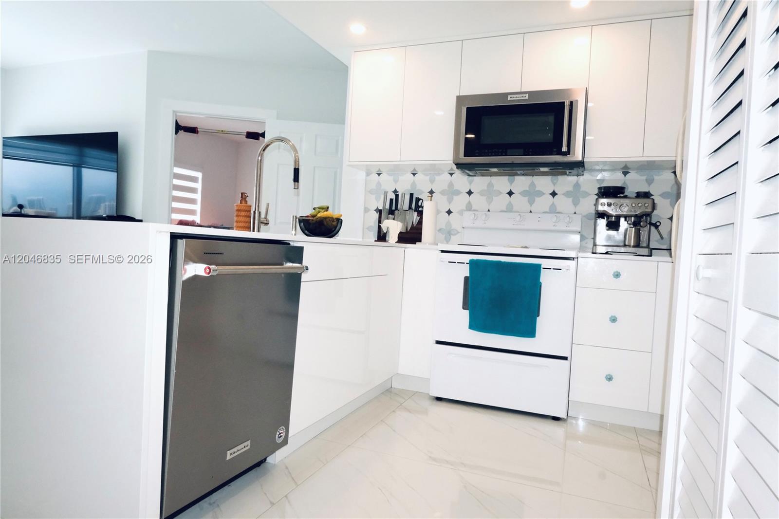 A modern kitchen features white cabinetry, stainless steel appliances, and a patterned tile backsplash — 3410 Coral Way # 05, Miami FL 33145, MIAMI, FL