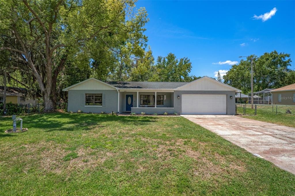 A single-story gray brick house with a white garage door and a covered front porch — 4737 KING LAKE DRIVE, LAND O LAKES, FL