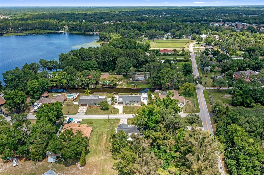 An aerial view shows houses situated near a lake, a canal, and a paved road — 4737 KING LAKE DRIVE, LAND O LAKES, FL