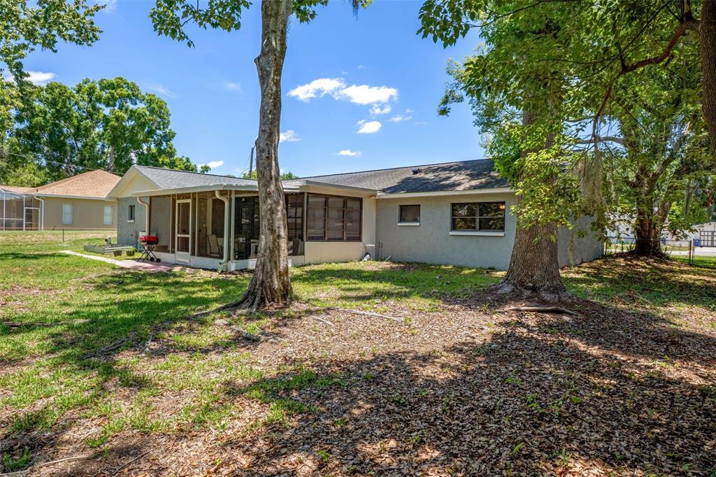 The exterior of a single-story house features a screened-in porch and large shade trees — 4737 KING LAKE DRIVE, LAND O LAKES, FL