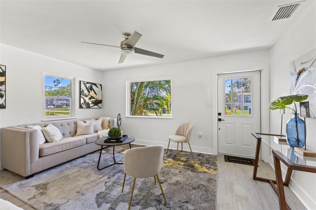 A living room features a beige sofa, a patterned area rug, and a ceiling fan — 6714 S FAUL STREET, TAMPA, FL