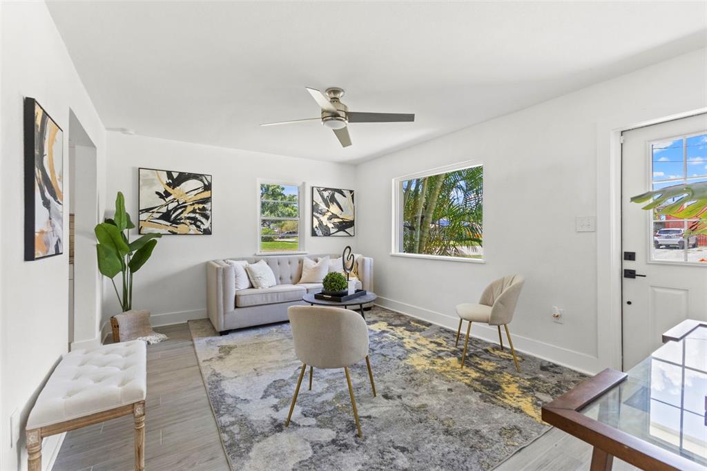 A bright living room features a tufted sofa, two accent chairs, and a patterned rug — 6714 S FAUL STREET, TAMPA, FL