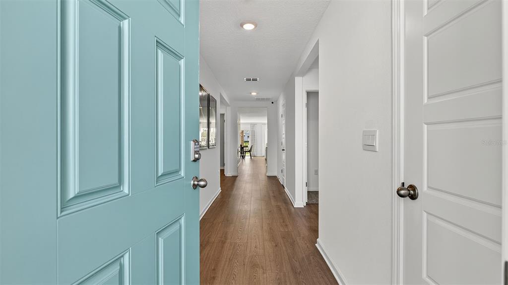 A view from an open light blue front door into a hallway with wood flooring — 70 BRIDGEHAVEN DRIVE, PALM COAST, FL