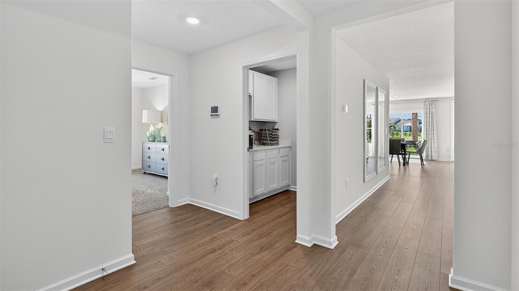 A hallway with wood-look flooring leads to a kitchen area and a dining room — 70 BRIDGEHAVEN DRIVE, PALM COAST, FL