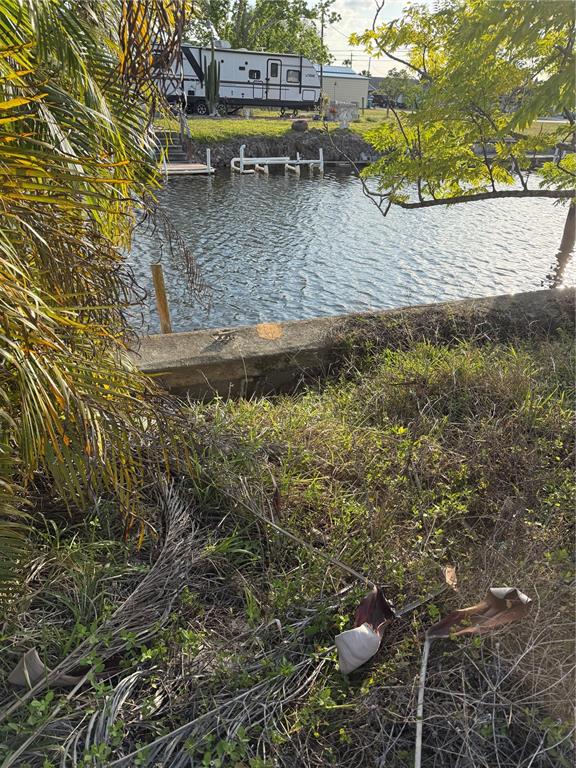 A view of a canal with a concrete seawall, dock pilings, and a parked RV — 4153 HOLLIS AVENUE, PORT CHARLOTTE, FL