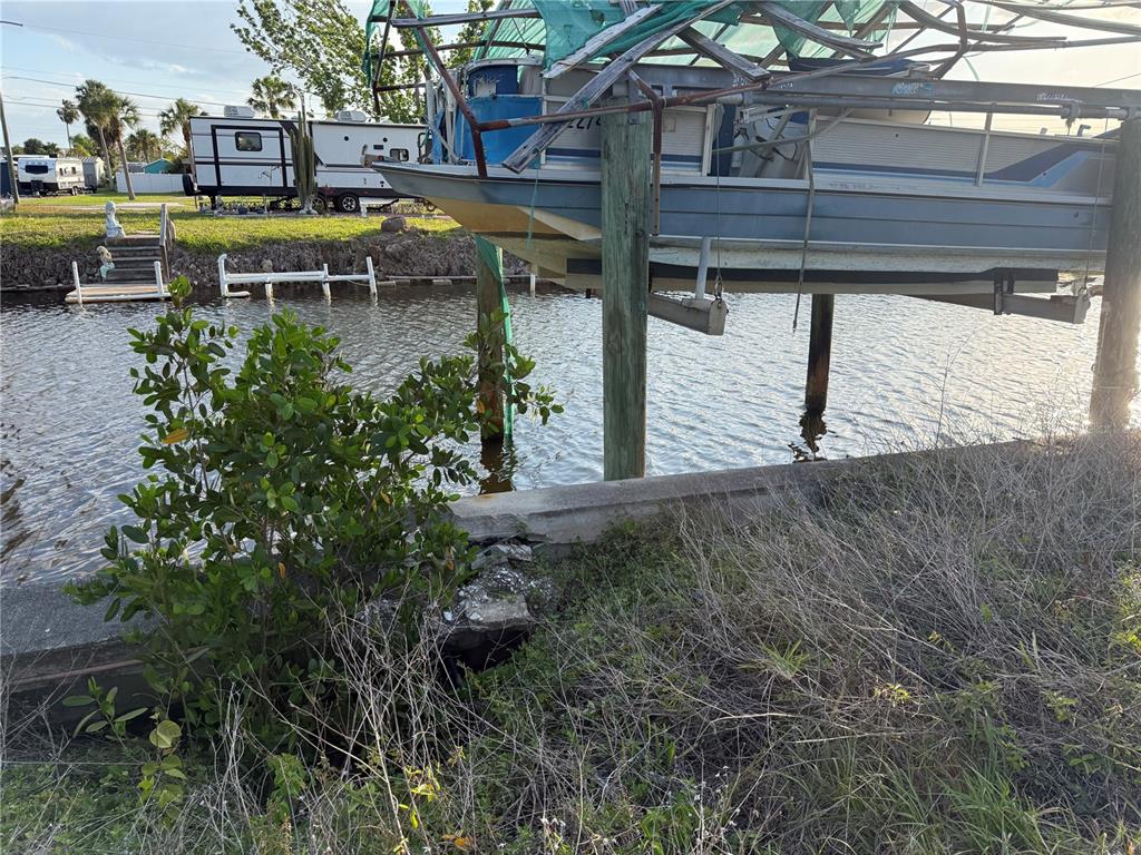 A pontoon boat sits on a lift above a canal next to a concrete seawall — 4153 HOLLIS AVENUE, PORT CHARLOTTE, FL