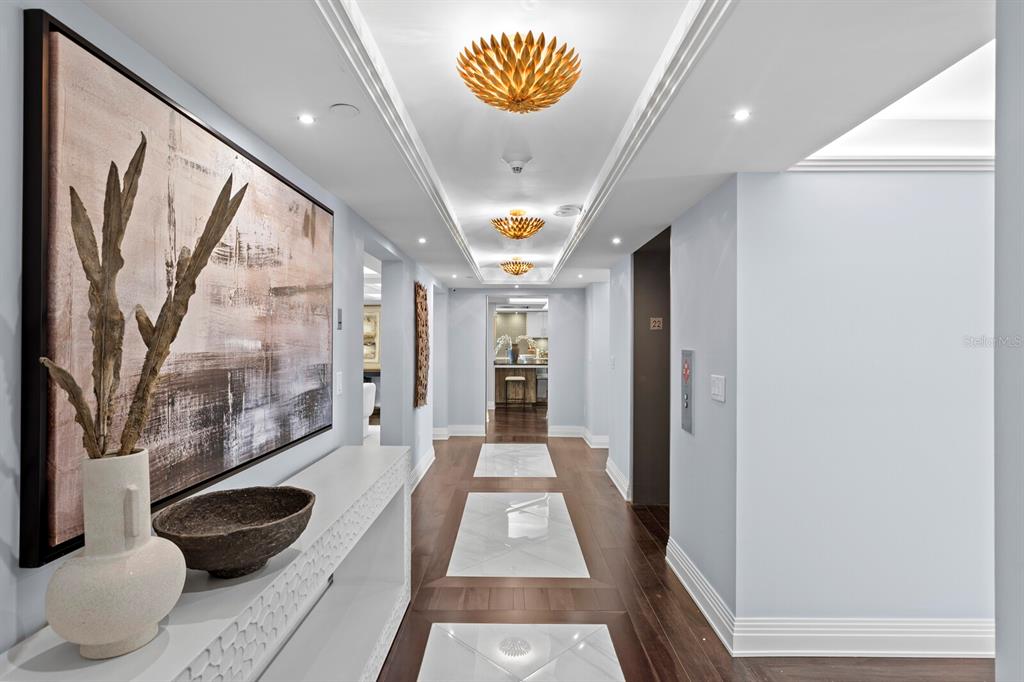 A hallway features a white console table, large abstract art, and marble floor inlays — 3301 BAYSHORE BOULEVARD UNIT 2207B, TAMPA, FL