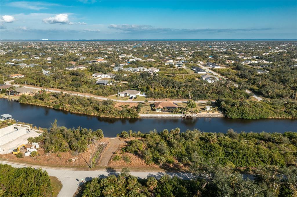 An aerial view shows a canal-front house surrounded by trees and a residential neighborhood — 10136 COCOA BEACH STREET, PORT CHARLOTTE, FL