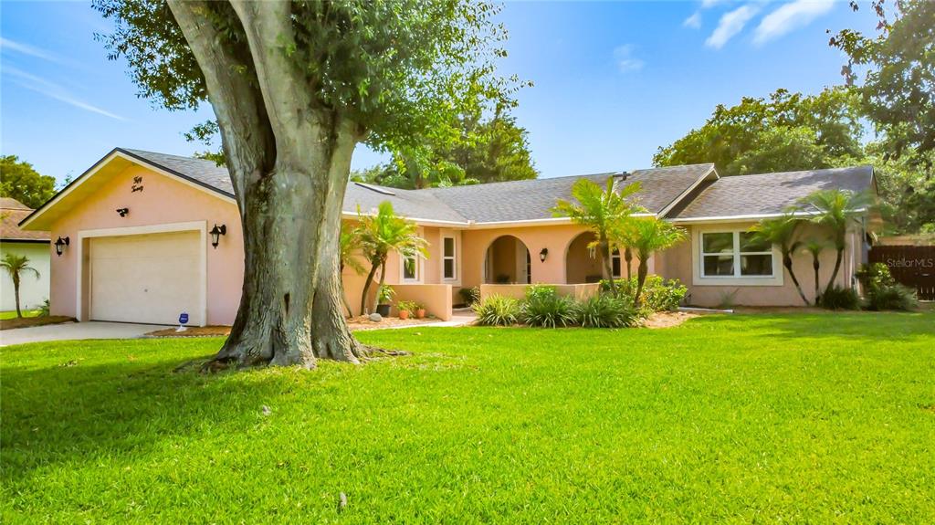 A single-story house with a pink exterior, a two-car garage, and a large front tree — 5020 THE OAKS CIRCLE, ORLANDO, FL