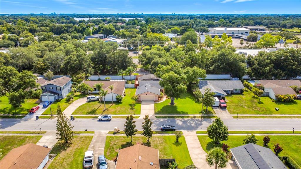 An aerial view shows a suburban street with single-family homes, green lawns, and mature trees — 5020 THE OAKS CIRCLE, ORLANDO, FL