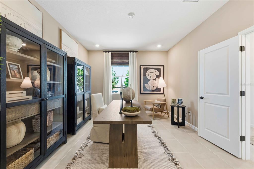 A home office features a wooden desk, two black glass-front cabinets, and a beige rug — 10653 NW SUNCREST LOOP, PORT ST LUCIE, FL