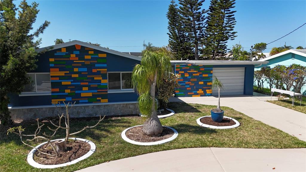 A single-story house features blue exterior walls with colorful rectangular accents and a garage — 4240 FLORAMAR TERRACE, NEW PORT RICHEY, FL