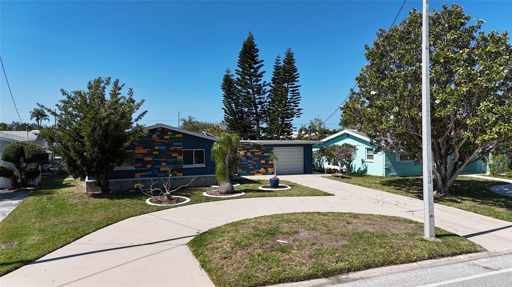 A blue house with a colorful brick-patterned facade and a curved concrete driveway — 4240 FLORAMAR TERRACE, NEW PORT RICHEY, FL