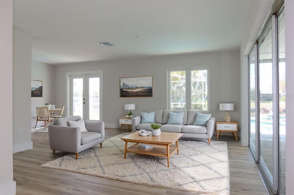 A living room with light wood floors, a gray sofa, and a large area rug — 4240 FLORAMAR TERRACE, NEW PORT RICHEY, FL