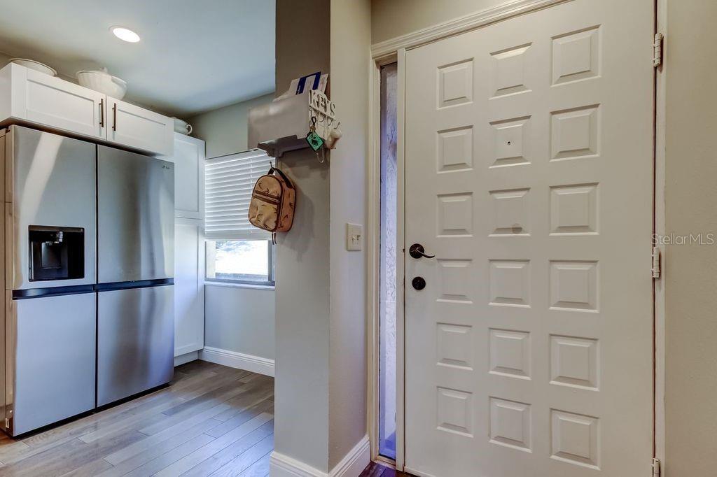 A stainless steel refrigerator stands next to a white door in a kitchen entryway — 3163 LANDMARK DRIVE UNIT 623, CLEARWATER, FL