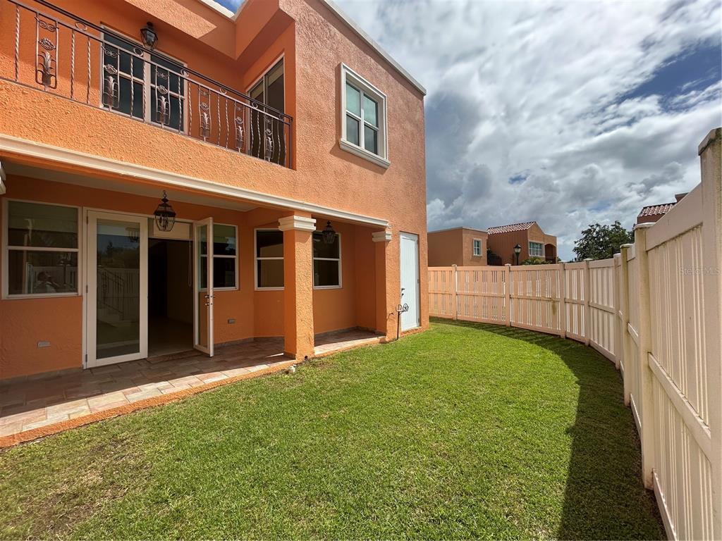 A two-story orange stucco house features a tiled patio and a fenced grassy backyard — C11 BRIGHTON COUNTRY CLUB, DORADO, PR