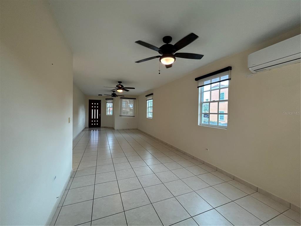 A long, tiled living area features three ceiling fans, white walls, and several windows — C11 BRIGHTON COUNTRY CLUB, DORADO, PR