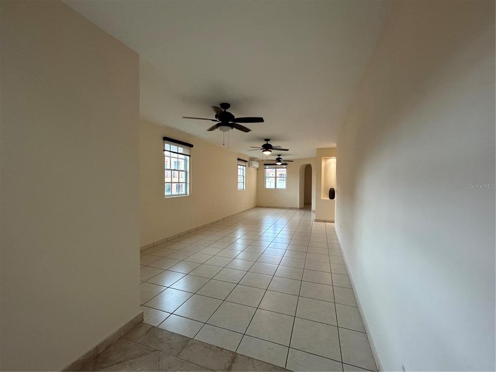 An empty, long room features light-colored tile flooring, white walls, and three ceiling fans — C11 BRIGHTON COUNTRY CLUB, DORADO, PR