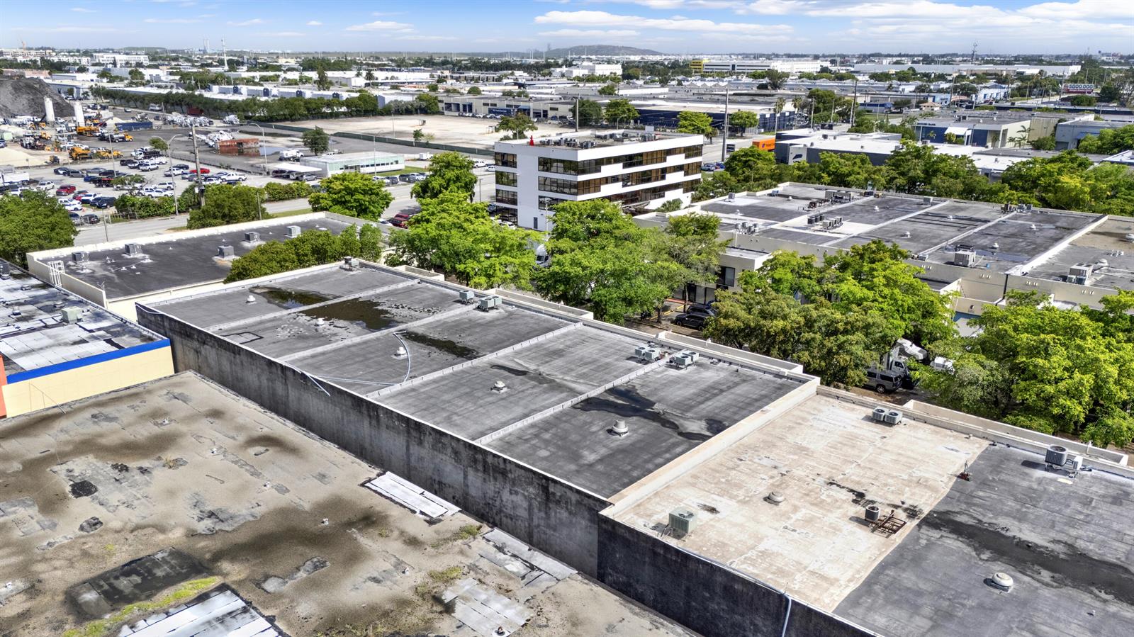An aerial view shows the flat, weathered roofs of several industrial buildings and surrounding trees — 7168 NW 50th Street, Miami FL 33166, MIAMI, FL