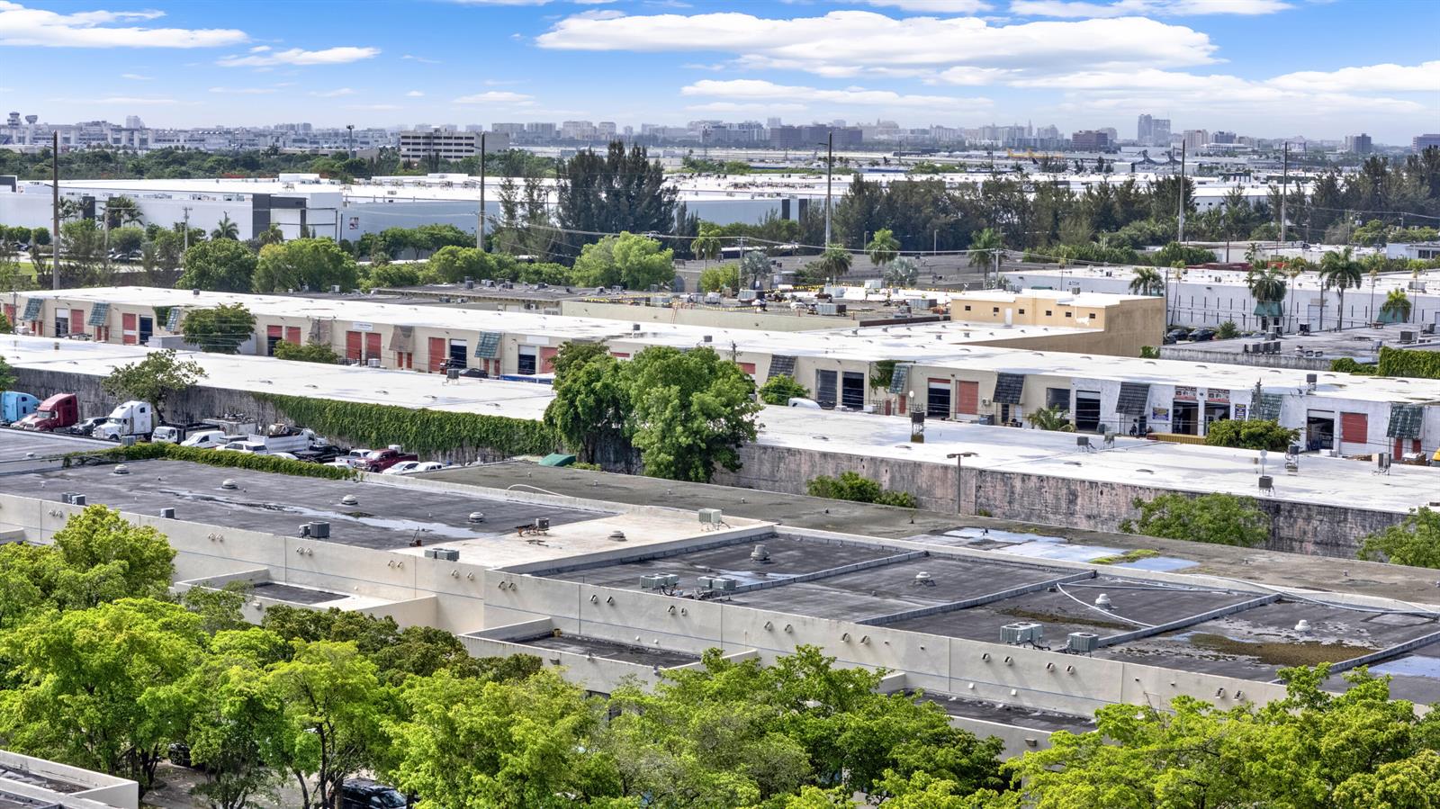 An elevated view of industrial warehouse buildings with flat roofs and surrounding green trees — 7168 NW 50th Street, Miami FL 33166, MIAMI, FL