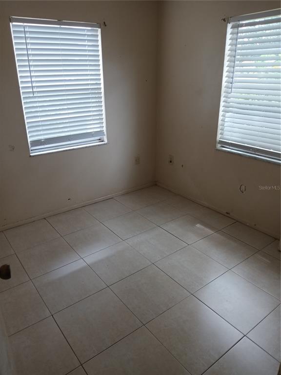 An empty room with light-colored tile flooring and two windows with white blinds — 1906 HONOUR ROAD UNIT 2, ORLANDO, FL