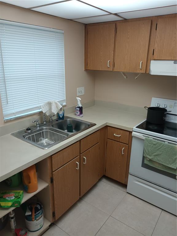 A kitchen features wood cabinets, a double-basin sink, a white stove, and tile flooring — 1906 HONOUR ROAD UNIT 2, ORLANDO, FL
