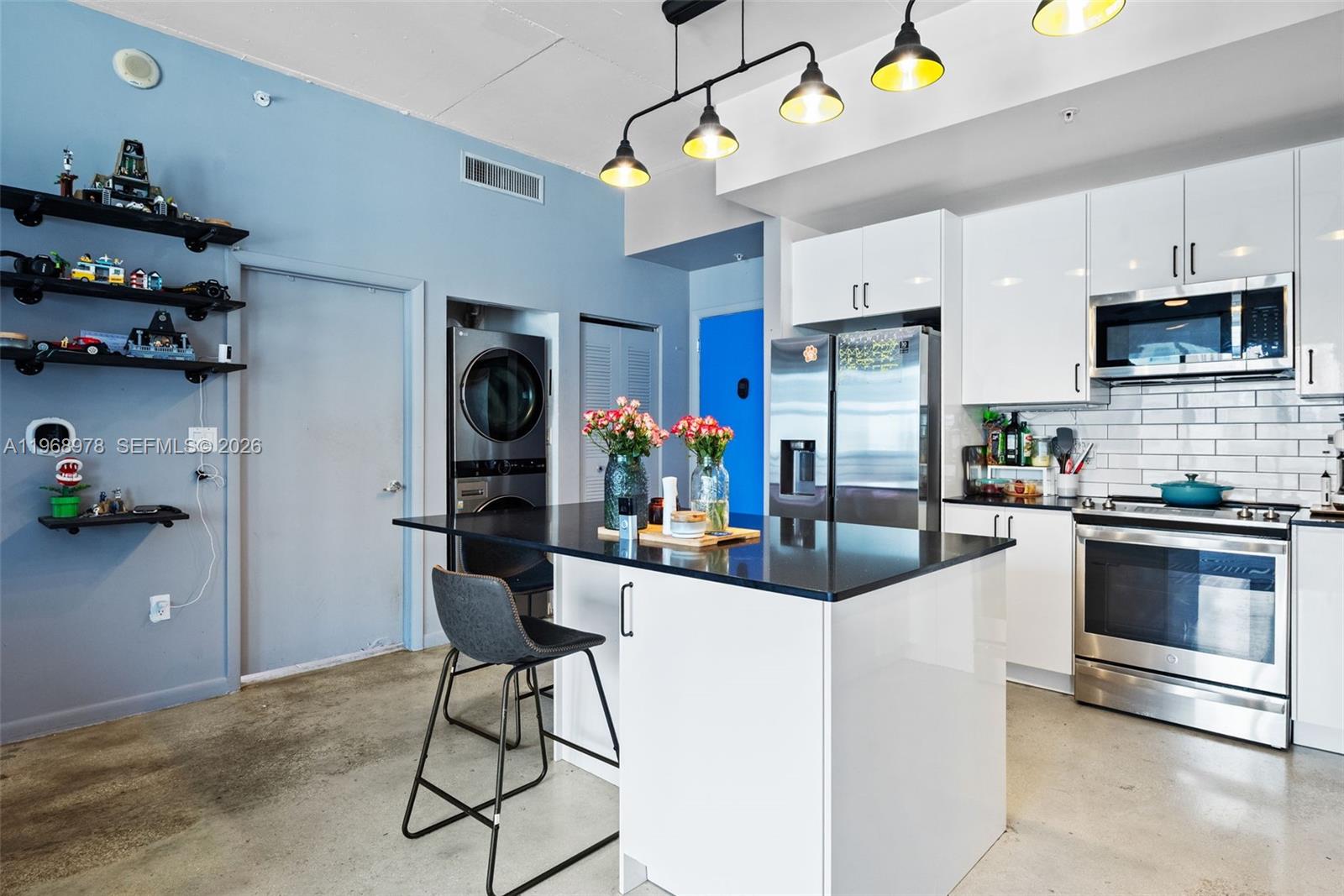 A modern kitchen features white cabinets, stainless steel appliances, a black island, and blue walls — 133 NE 2nd Ave # 1606, Miami FL 33132, MIAMI, FL
