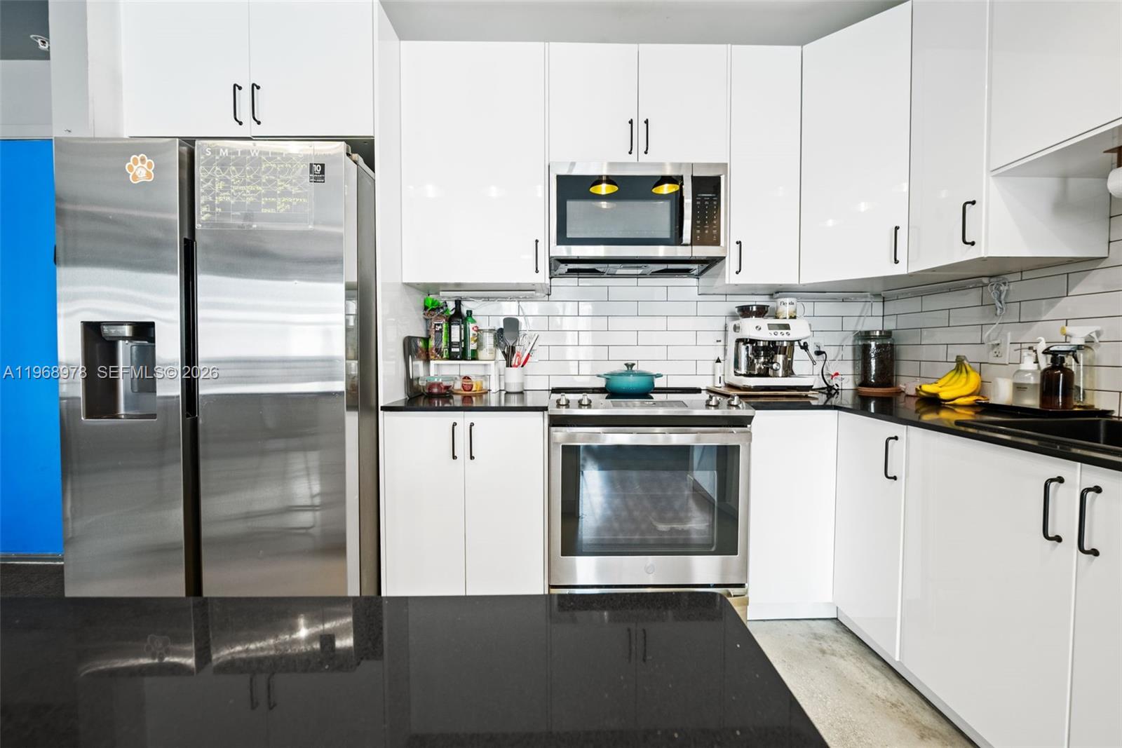A modern kitchen features white cabinets, stainless steel appliances, and black countertops — 133 NE 2nd Ave # 1606, Miami FL 33132, MIAMI, FL