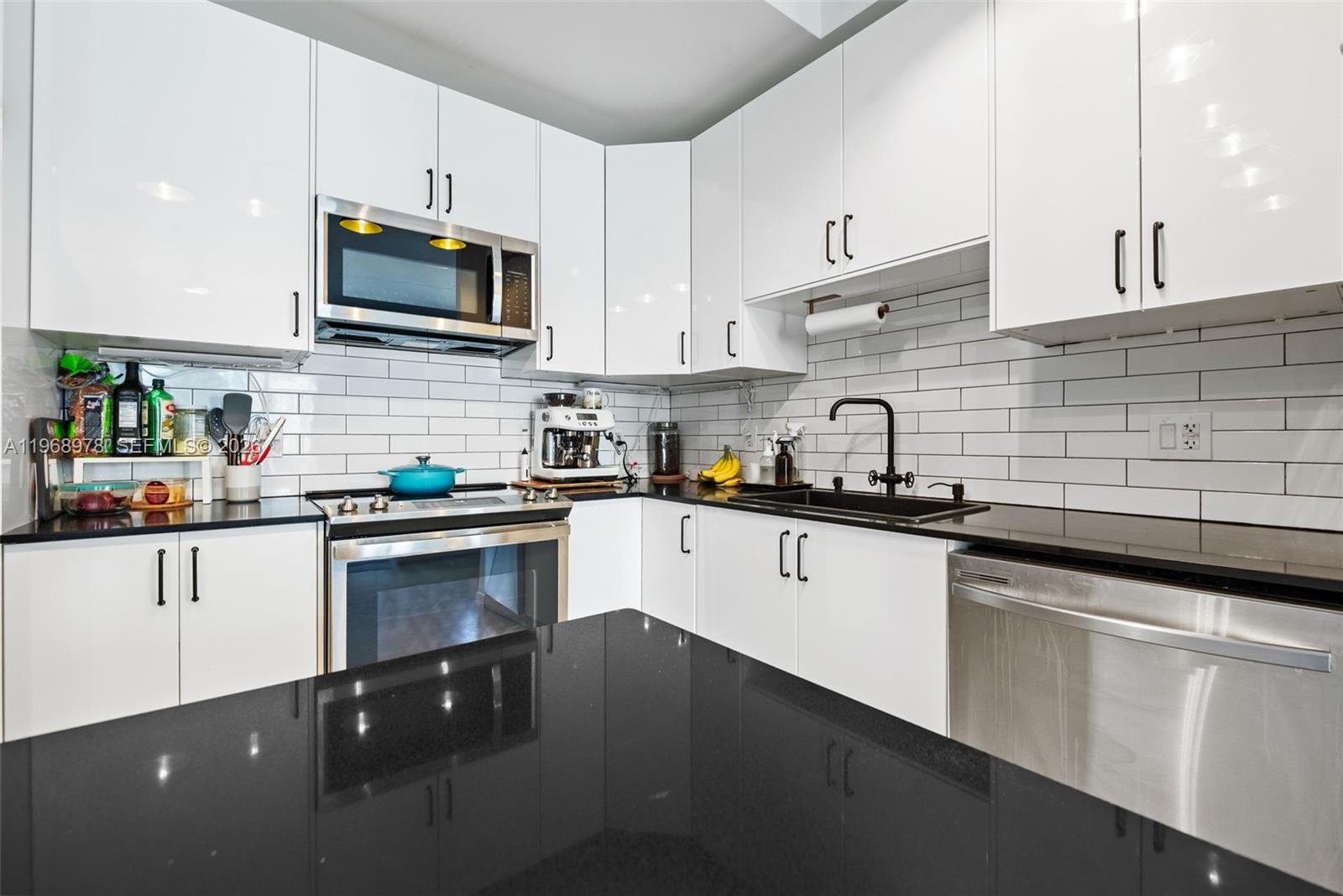 A modern kitchen features white cabinets, black countertops, stainless steel appliances, and white subway tile — 133 NE 2nd Ave # 1606, Miami FL 33132, MIAMI, FL
