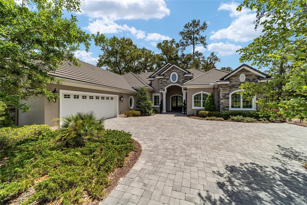 A single-story house with a stone facade, tiled roof, and a paved circular driveway — 7554 NW 33RD PLACE, OCALA, FL