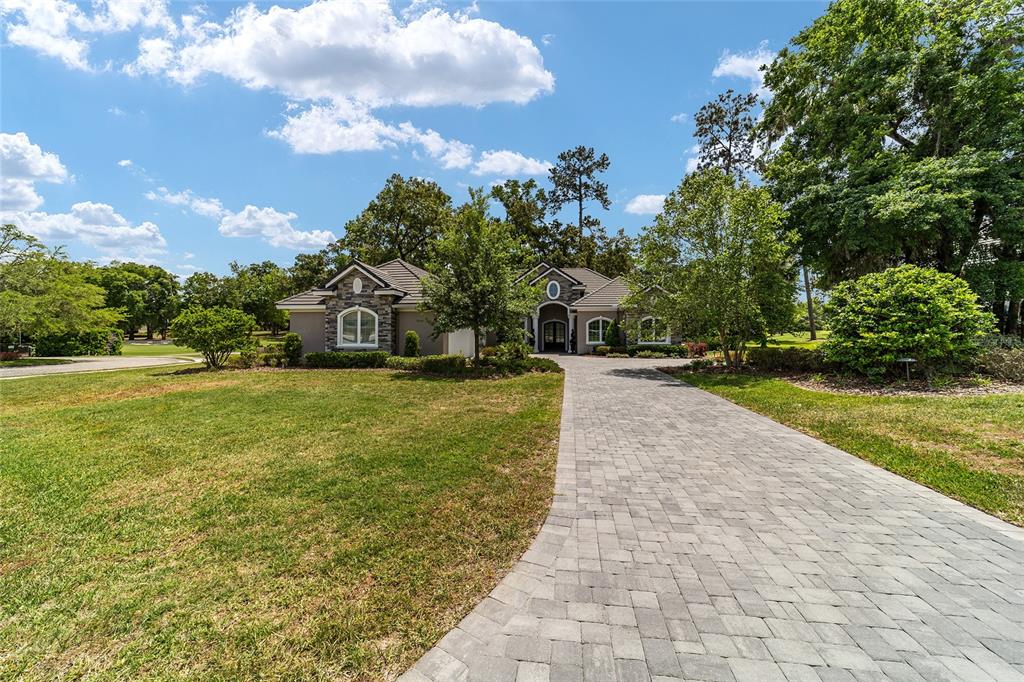 A single-story house with a stone facade and a paved driveway under a blue sky — 7554 NW 33RD PLACE, OCALA, FL