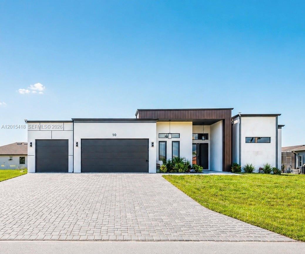 A modern single-story house features a paved driveway, a three-car garage, and white stucco walls — 10 SW 33rd PL, Cape Coral FL 33904, CAPE CORAL, FL