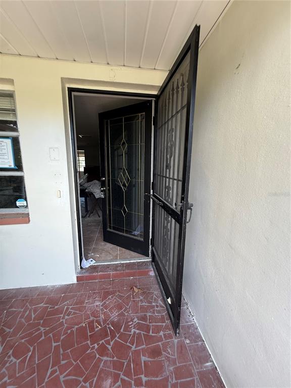 An open security door leads to an entryway with a glass-paneled front door — 8335 GULF WAY, HUDSON, FL