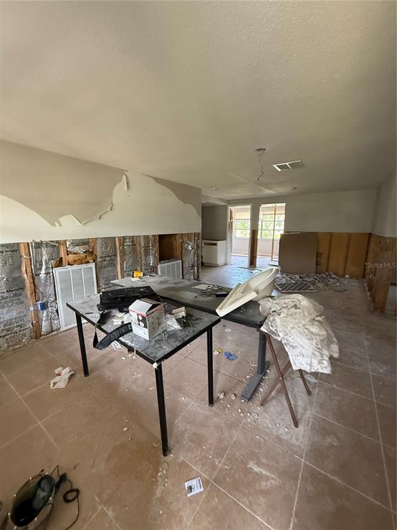 An interior room undergoing renovation with exposed wall studs, damaged drywall, and construction debris — 8335 GULF WAY, HUDSON, FL