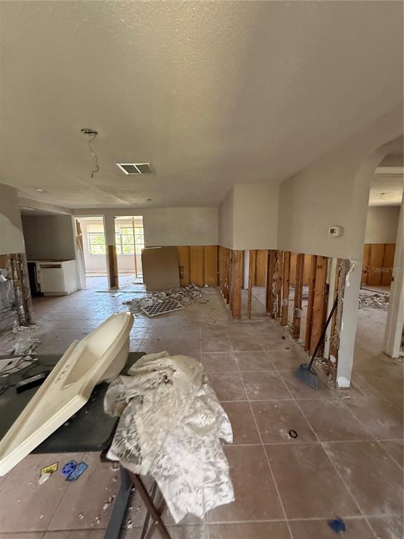An interior room under renovation features exposed wall studs, tiled flooring, and a detached bathtub — 8335 GULF WAY, HUDSON, FL