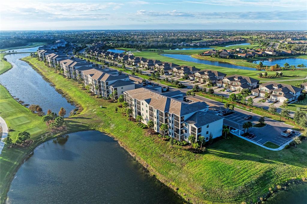 An aerial view shows multi-story apartment buildings situated along a lake and golf course — 18114 GAWTHROP DRIVE UNIT 204, BRADENTON, FL