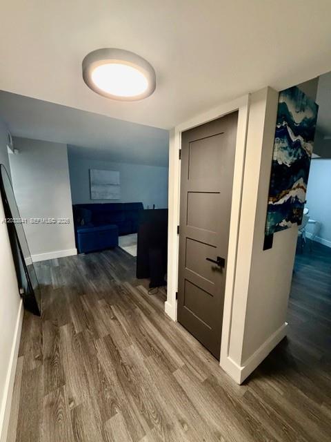 A hallway with wood-look flooring leads to a living area with a blue sofa — 5800 CAMINO REAL # 306, Boca Raton FL 33433, BOCA RATON, FL